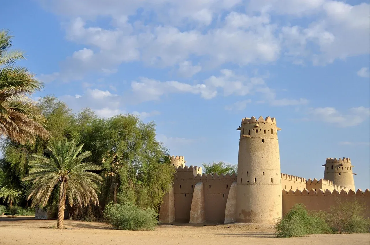 Round watchtower of Al Jahili Fort rising over palm trees in Al Ain