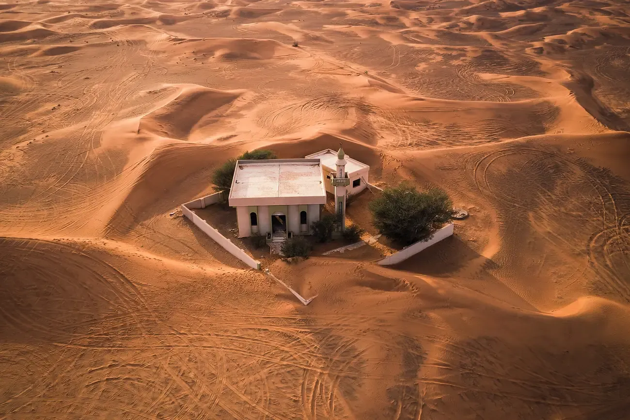 A house of the Al Madam ghost village half buried by dunes