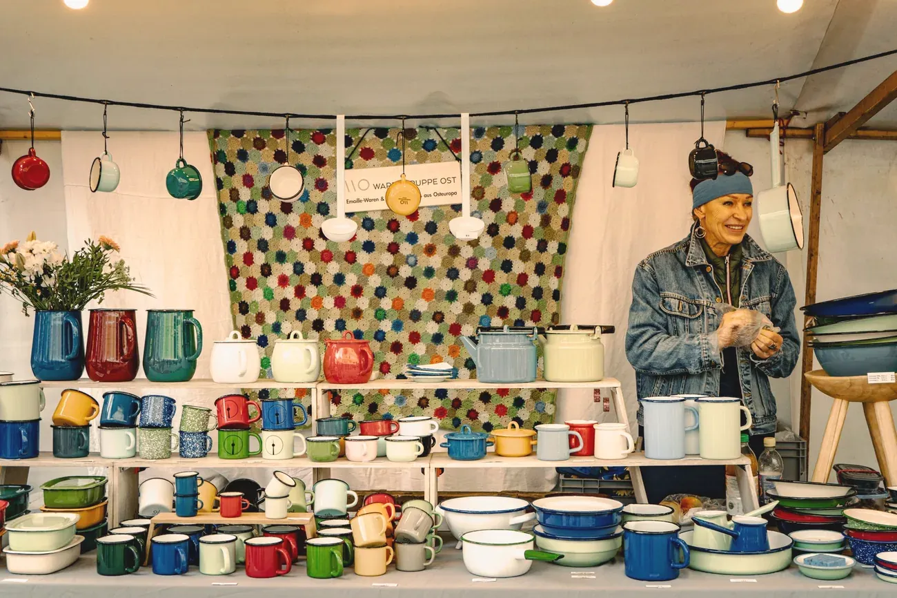 A maker selling enamel mugs and pots at a craft market stall