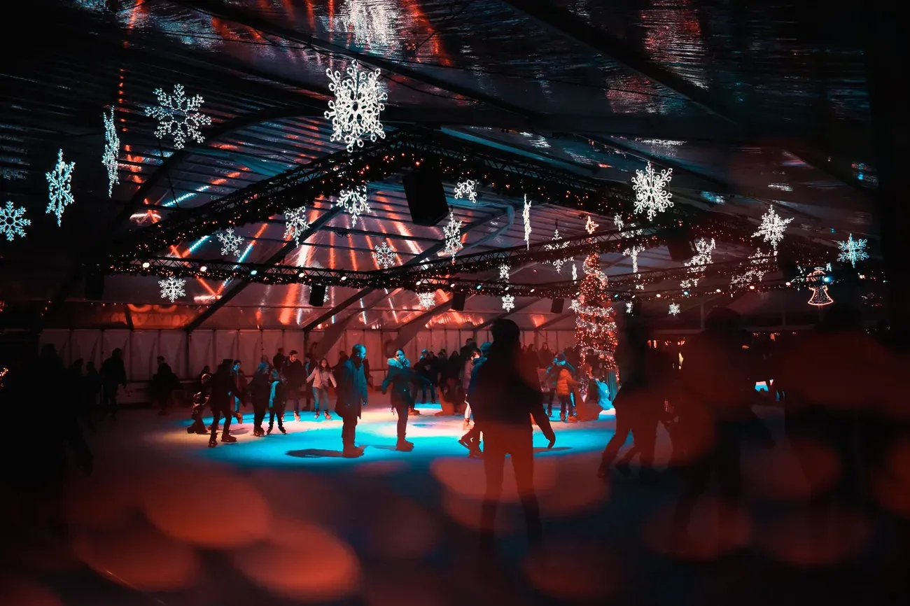 Visitors skating on an indoor ice rink under snowflake Christmas lights