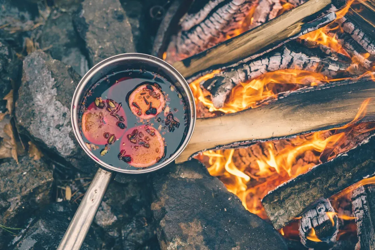 A pot of mulled wine simmering over a campfire