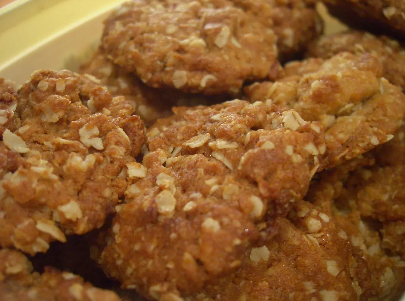 Anzac biscuits made with rolled oats and golden syrup cooling on a tray