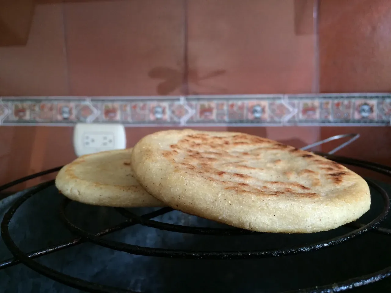 Corn arepas cooking on a hot griddle