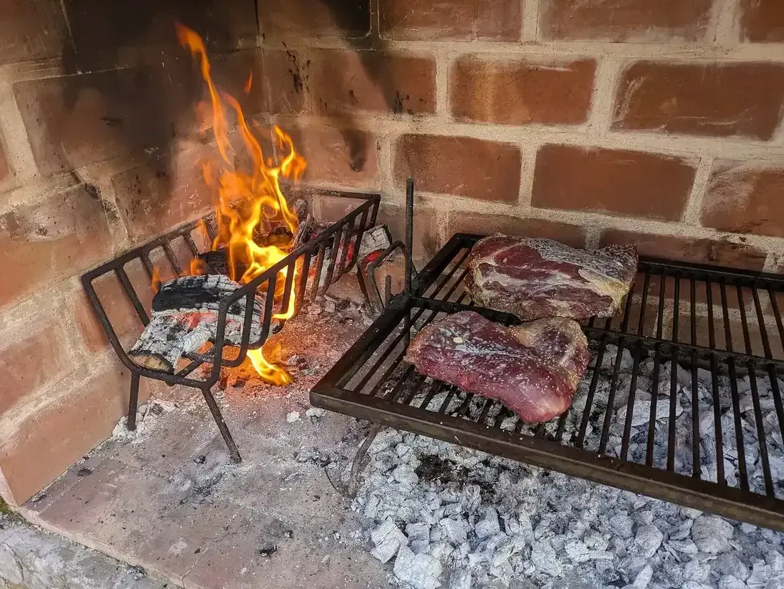 Cuts of beef on a parrilla over wood embers, a traditional Argentine asado