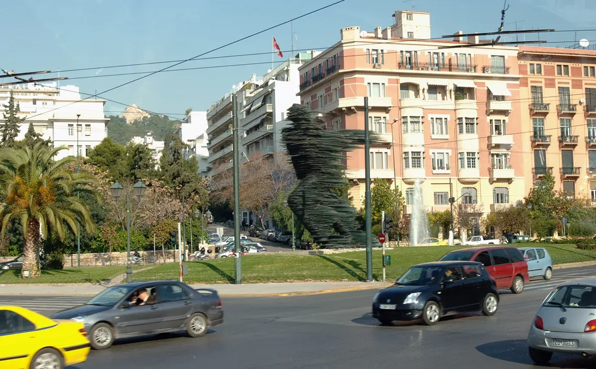 The Runner glass sculpture by Costas Varotsos on its traffic island beside a busy avenue in Athens