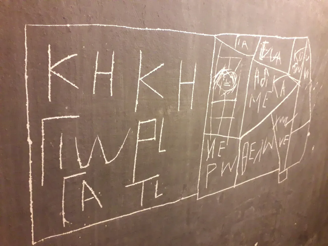 Messages and drawings scratched into a wall by prisoners at the Korai 4 memorial site in Athens