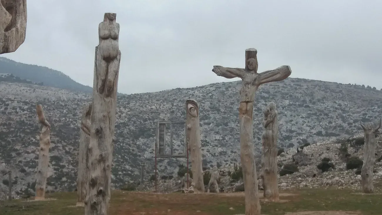Carved wooden figures standing on the mountainside at the Park of Souls on Mount Parnitha