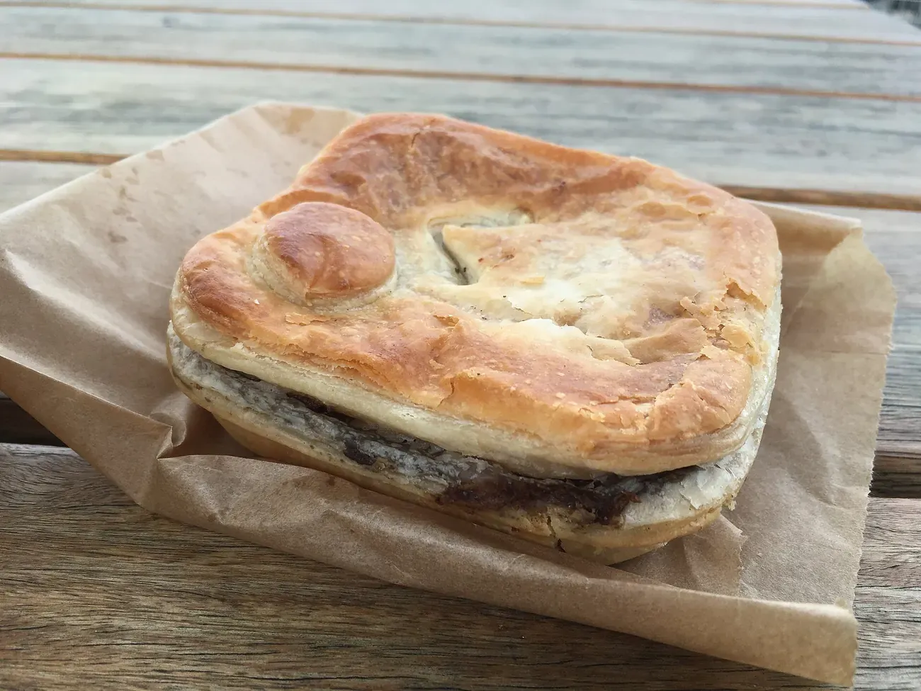 An Australian meat pie served in paper from a country bakery