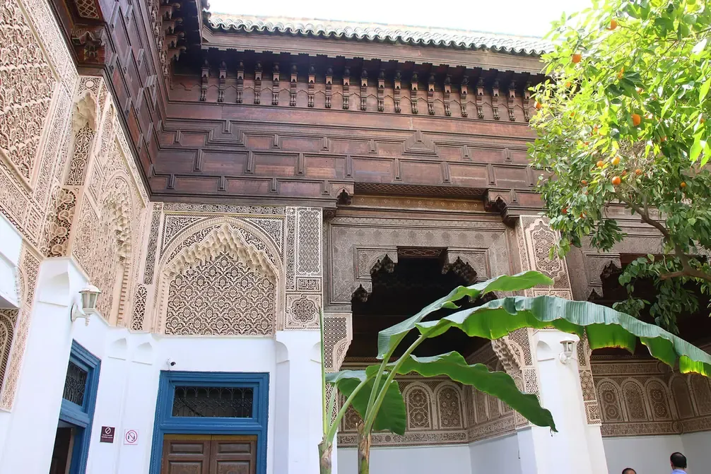 Carved cedar and painted stucco beside a blue door at the Bahia Palace in Marrakech