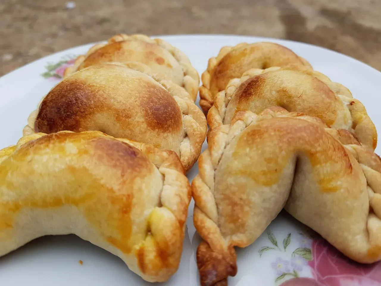 Baked salteñas with their braided seam on a plate, Bolivia
