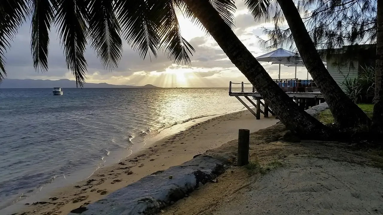A beach and small jetty at dusk in the Fiji islands