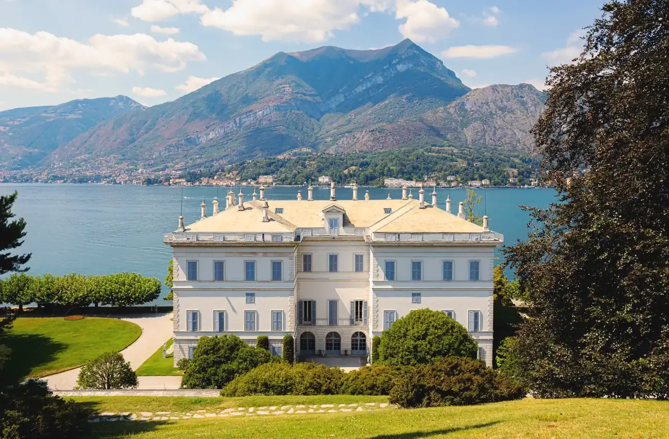 The white neoclassical Villa Melzi d'Eril in Bellagio above its lawn, with Lake Como behind