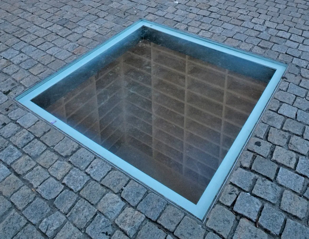 The glass pane in the pavement of Bebelplatz in Berlin looking down into the empty white shelves of the book-burning memorial