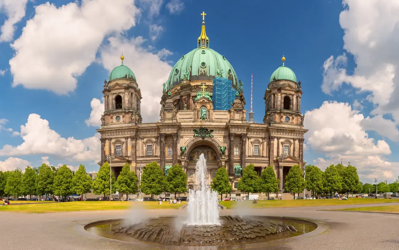 The main facade and green dome of Berlin Cathedral seen across the Lustgarten fountain on Museum Island