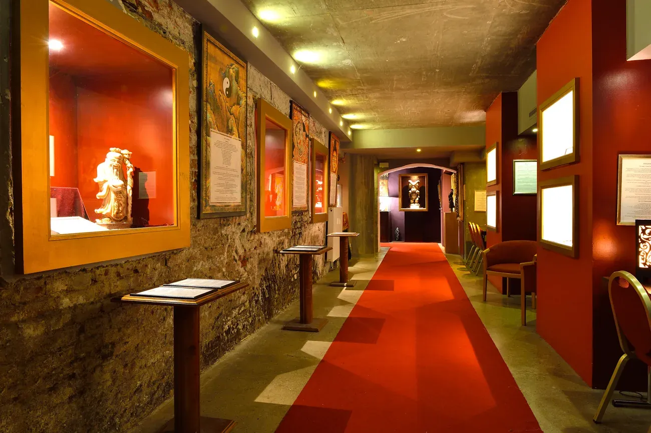 Red lit exhibition corridor lined with display cases of magic and superstition artefacts inside the Magicum museum in Berlin
