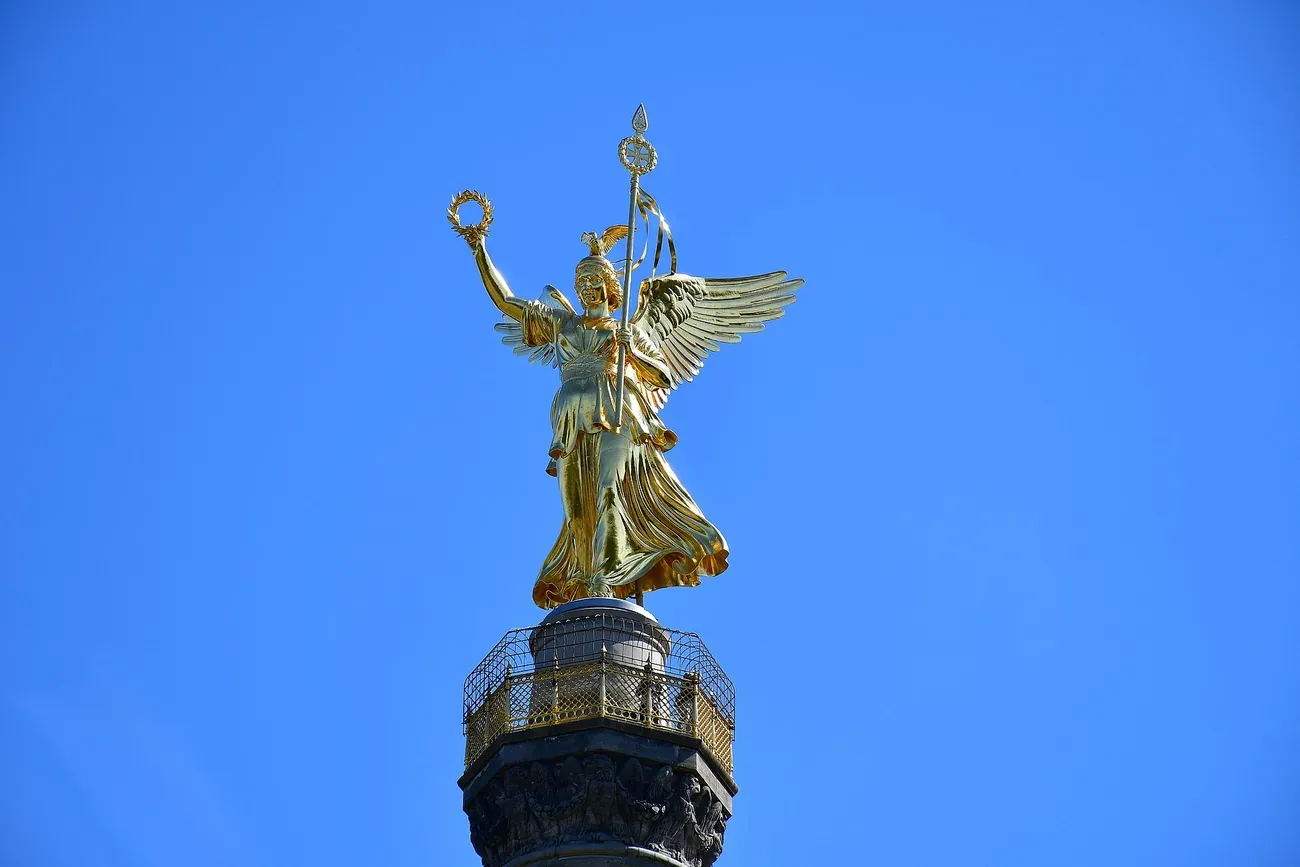 The gilded statue of Victoria on top of the Berlin Victory Column against a clear blue sky