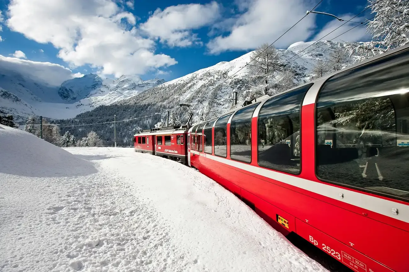 Bernina Express panoramic carriages running through deep winter snow below glaciated peaks
