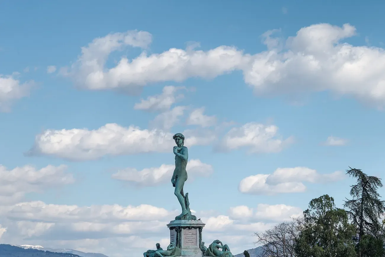 The bronze replica of Michelangelo's David on its monument at Piazzale Michelangelo seen in profile against a cloudy sky in Florence