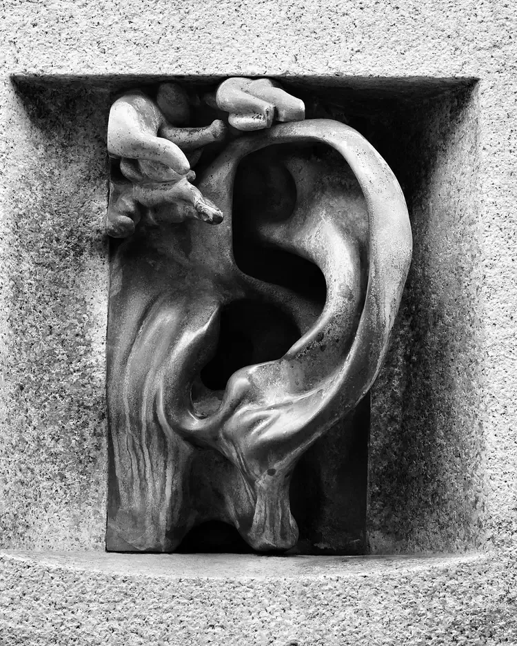 Bronze ear sculpture set in a stone niche on the facade of Casa Sola-Busca in Via Serbelloni, Milan