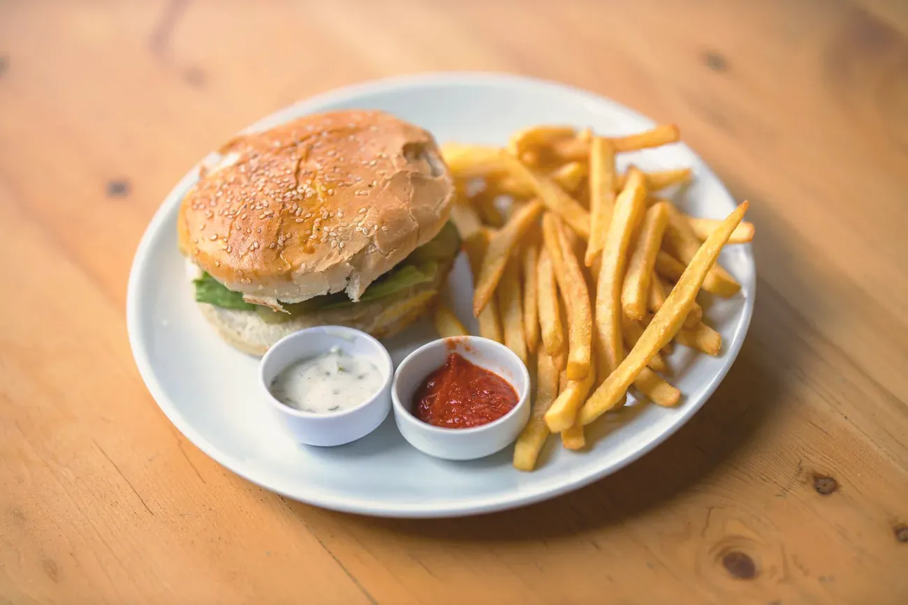 Burger and chips with two dips on a white plate
