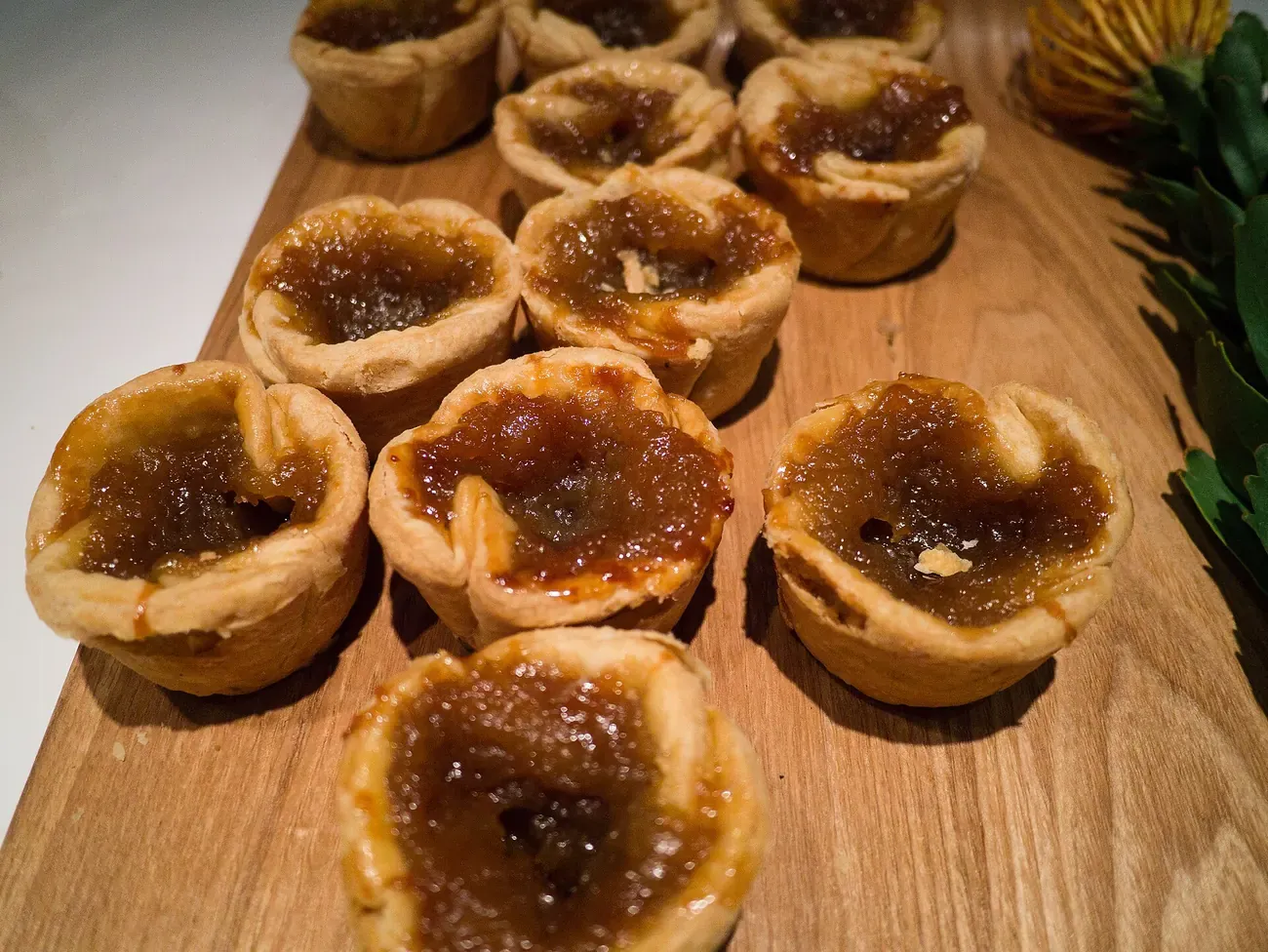 Butter tarts with their filling set and crisp on a wooden board
