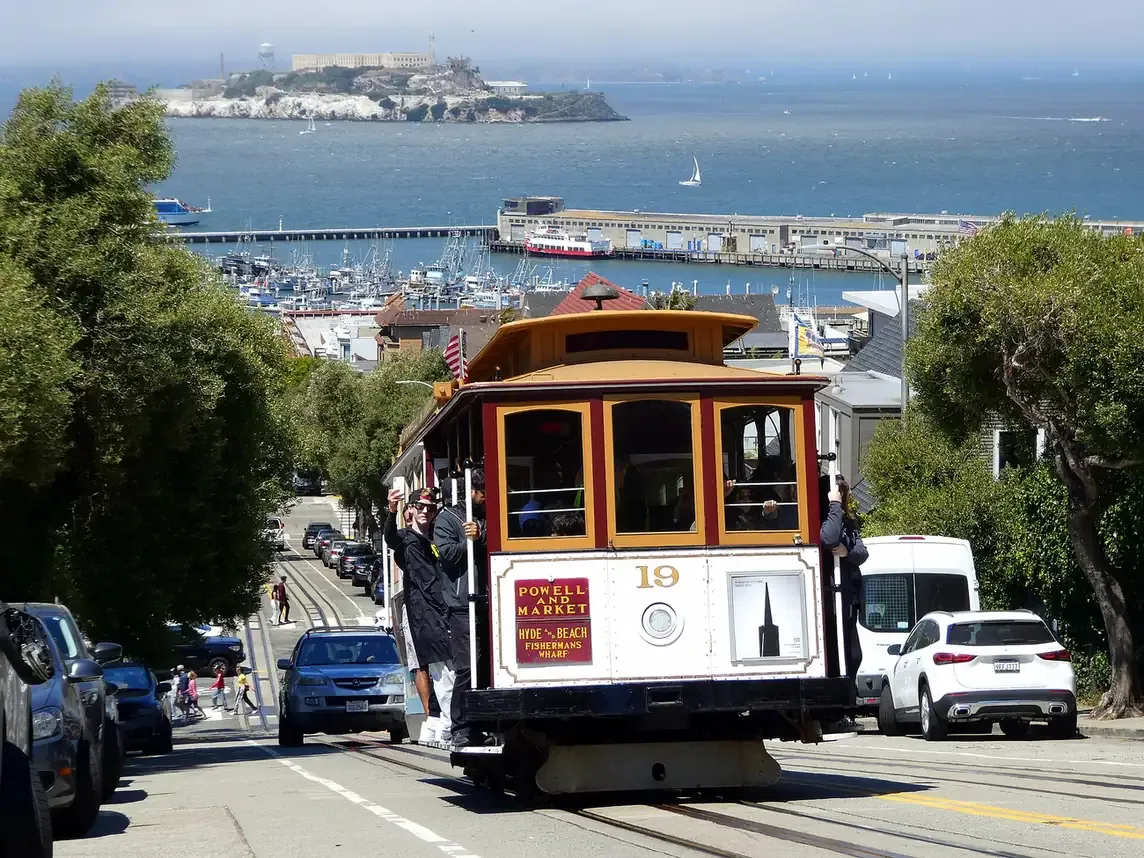 A San Francisco cable car climbing Hyde Street with Alcatraz and the bay behind