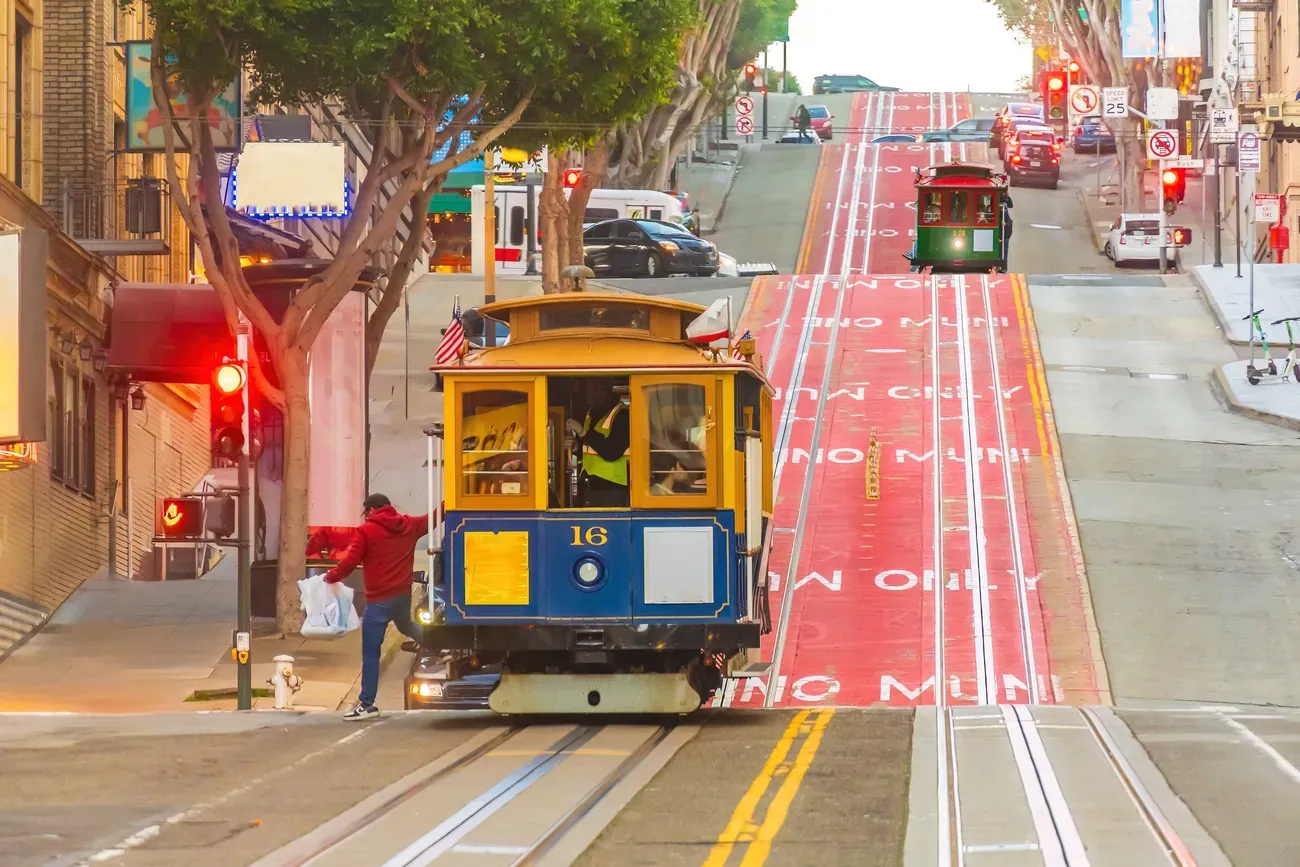 A cable car climbing a steep street in San Francisco between the painted transit lanes