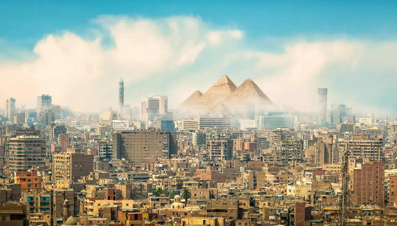 The dense city of Cairo with the pyramids on the hazy horizon