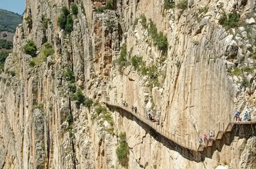 Walkers on the Caminito del Rey boardwalk pinned to the limestone wall of the Gaitanes gorge in Malaga province