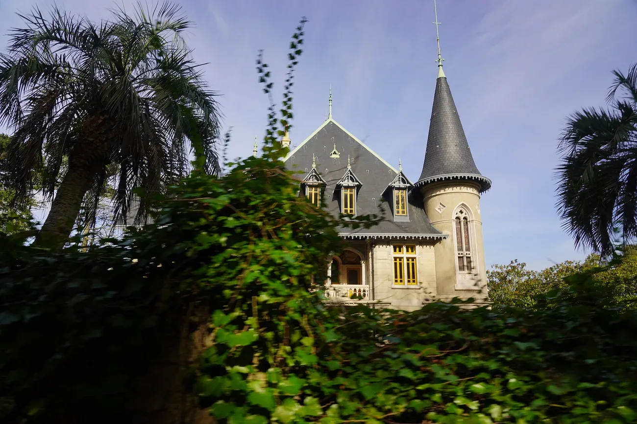 The Gothic Revival turret of Casa Biester rising above palm trees in its wooded park in Sintra