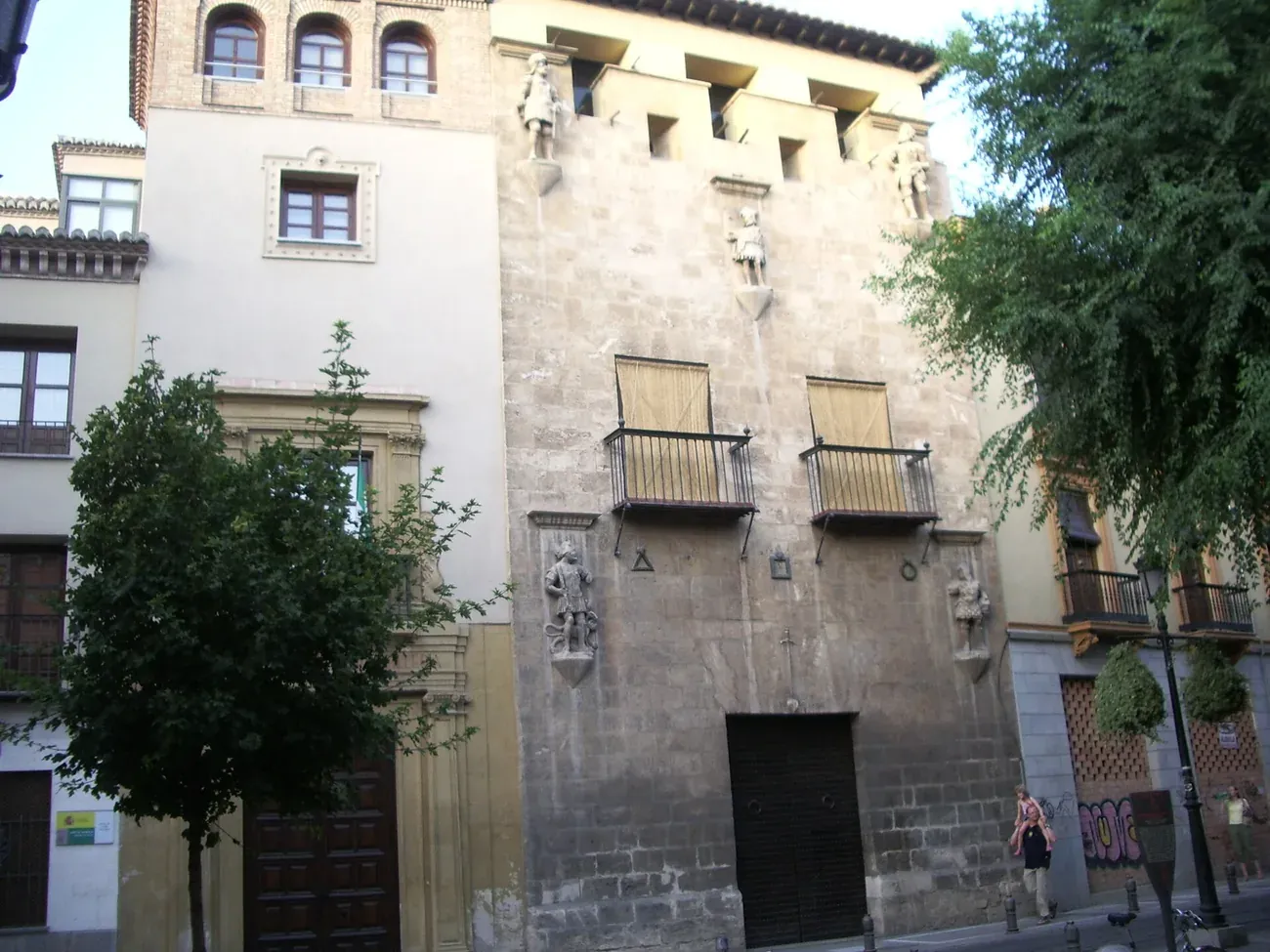 Fortified stone facade of the Casa de los Tiros in Granada with statues and the crenellated top