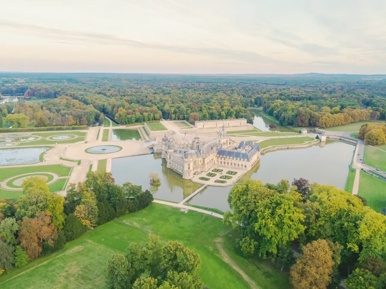 Aerial view of the Chateau de Chantilly on its water with the formal park and forest, France