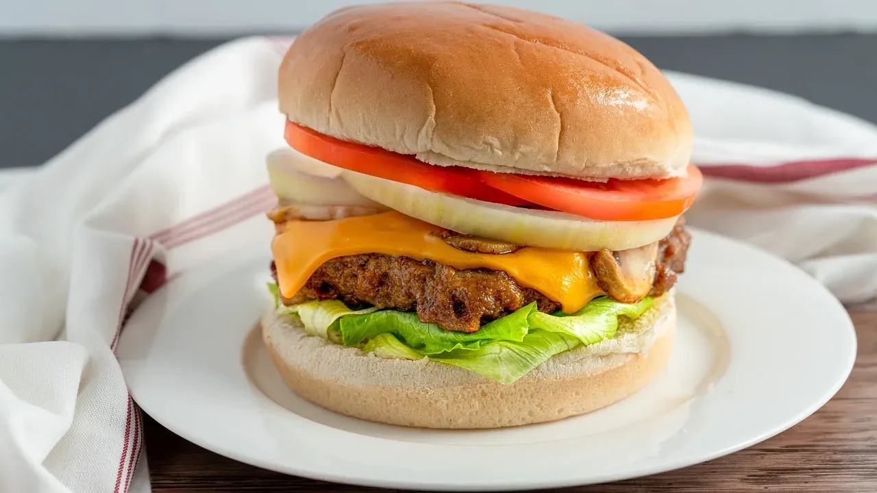 A cheeseburger with melted cheese, tomato and lettuce on a plate