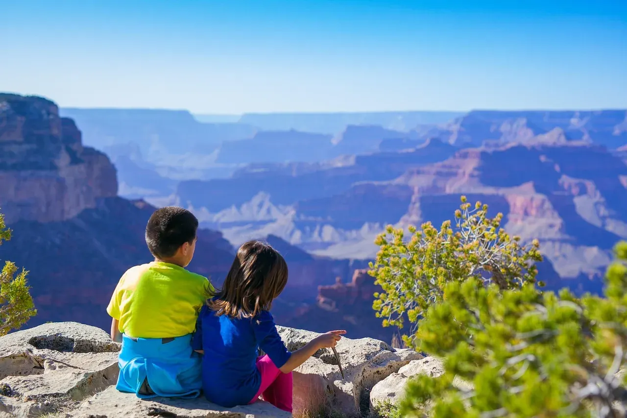 Two children sitting on the rim looking over the Grand Canyon in Arizona