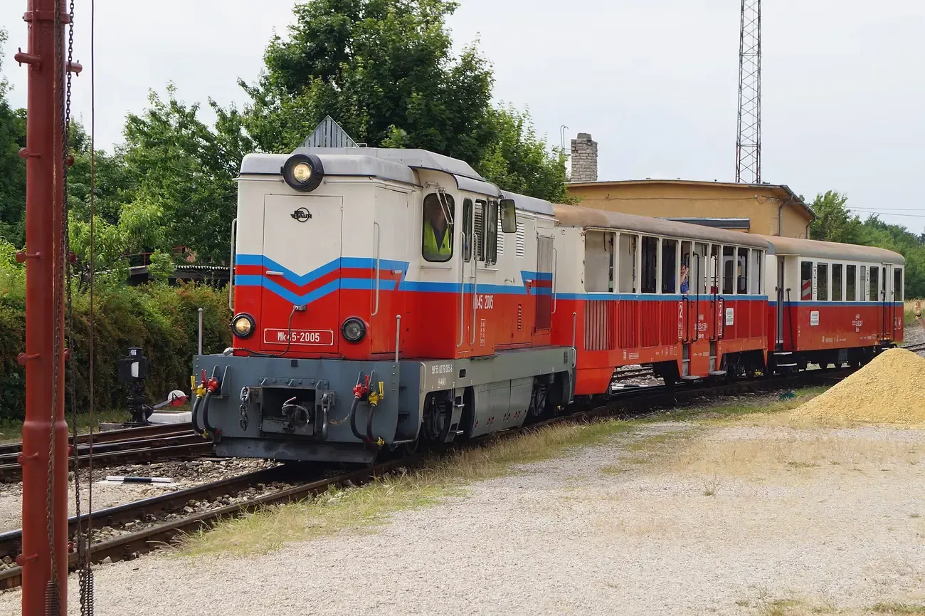 A red and cream diesel locomotive pulling coaches on the Children's Railway in the Buda hills of Budapest