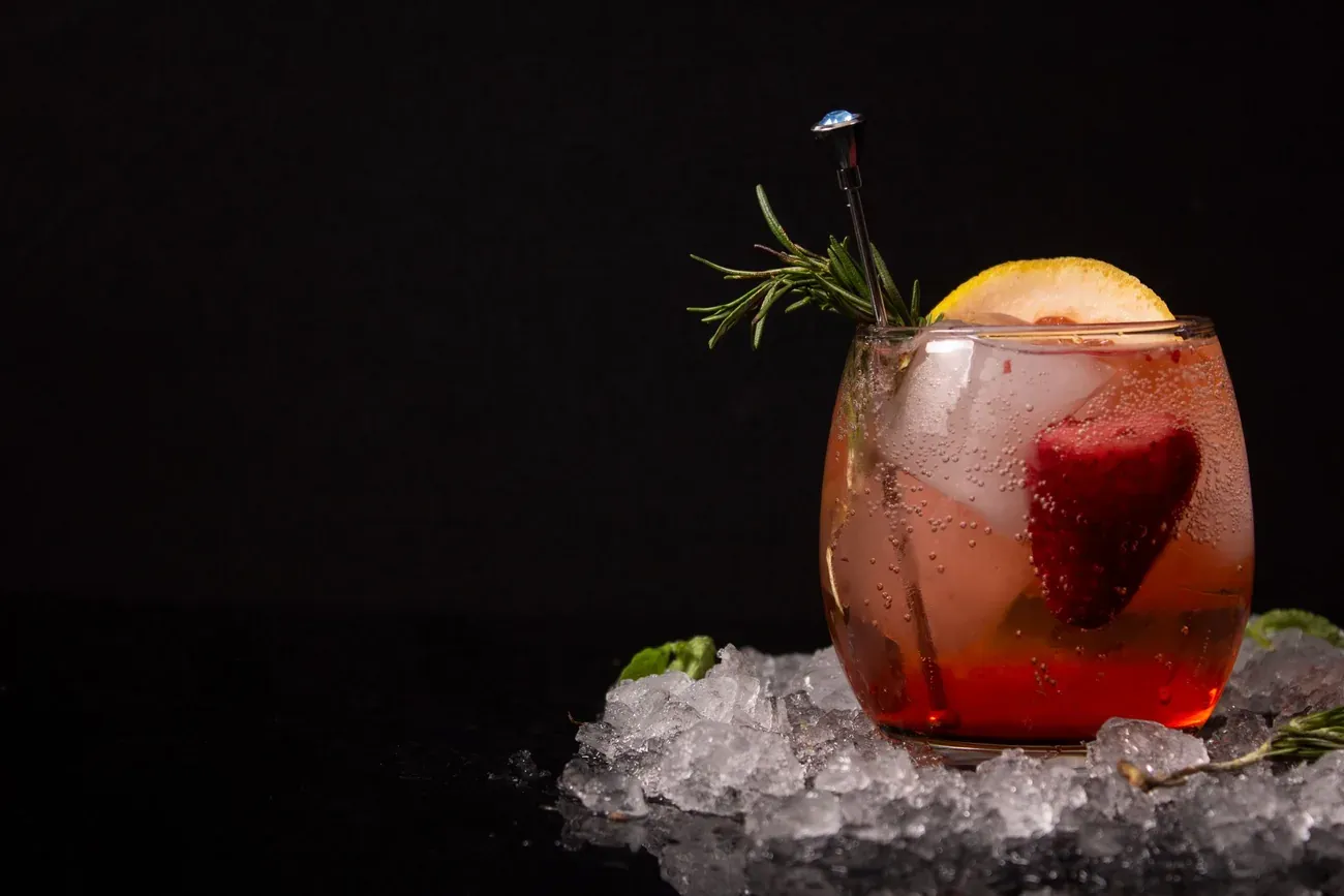 Chilled cocktail with lemon, strawberry and rosemary on crushed ice