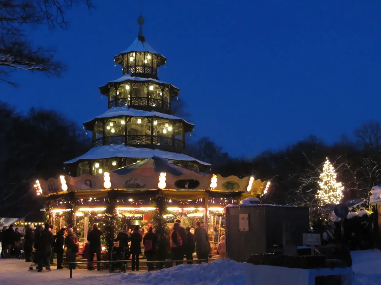 The lit Chinese Tower above the Christmas market in the English Garden at dusk, Munich