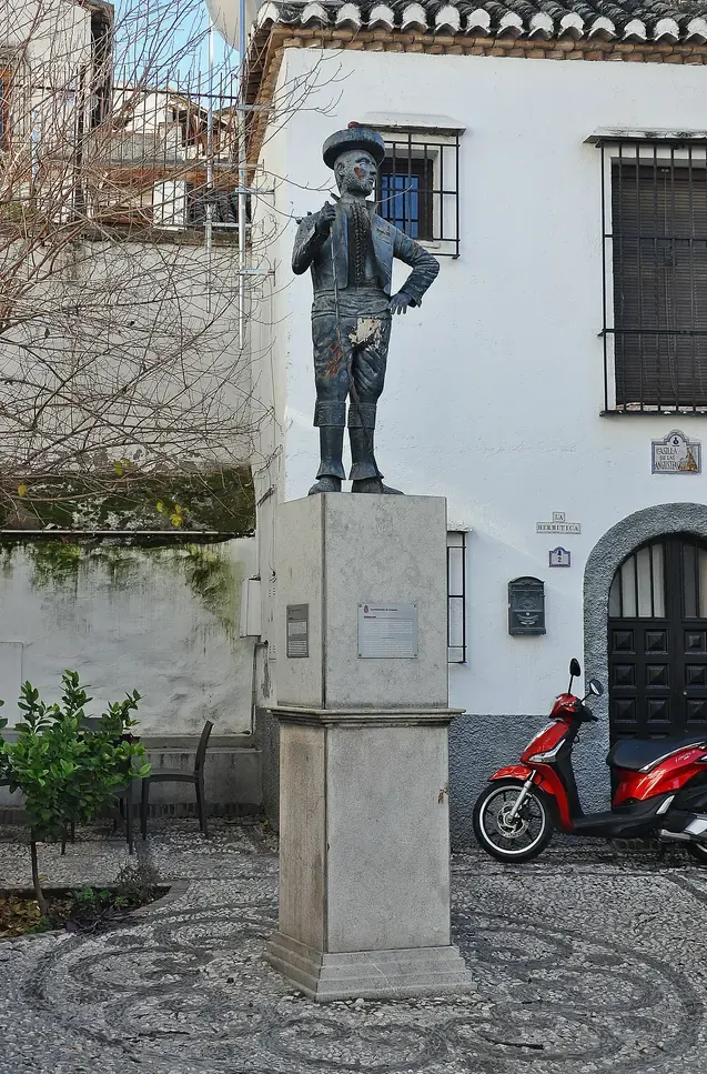 Bronze statue of Chorrojumo on a stone pedestal in a small cobbled square of the Albaicin in Granada