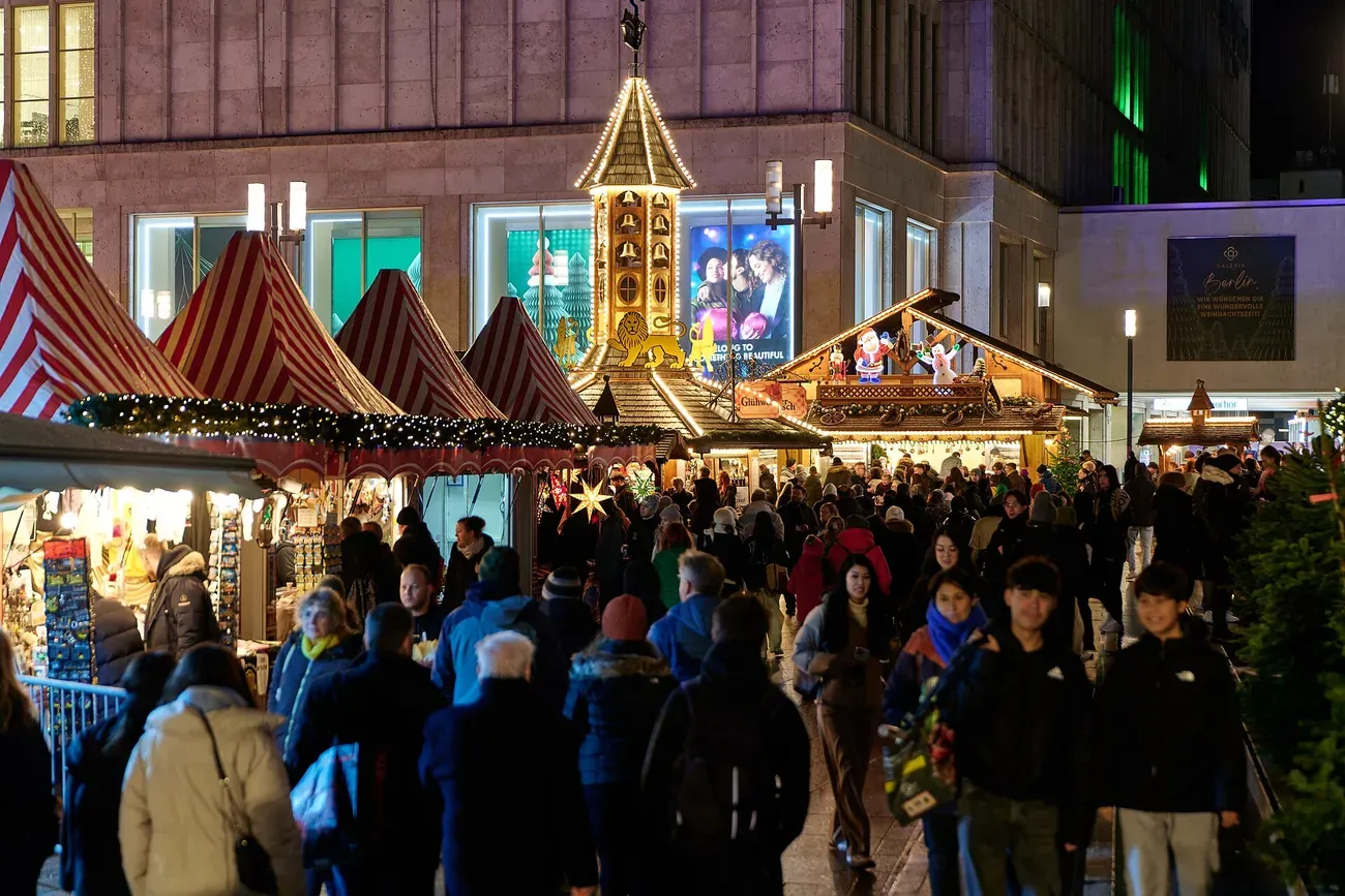 Striped stall roofs and a lit tower at the 2024 Christmas market on Alexanderplatz, Berlin