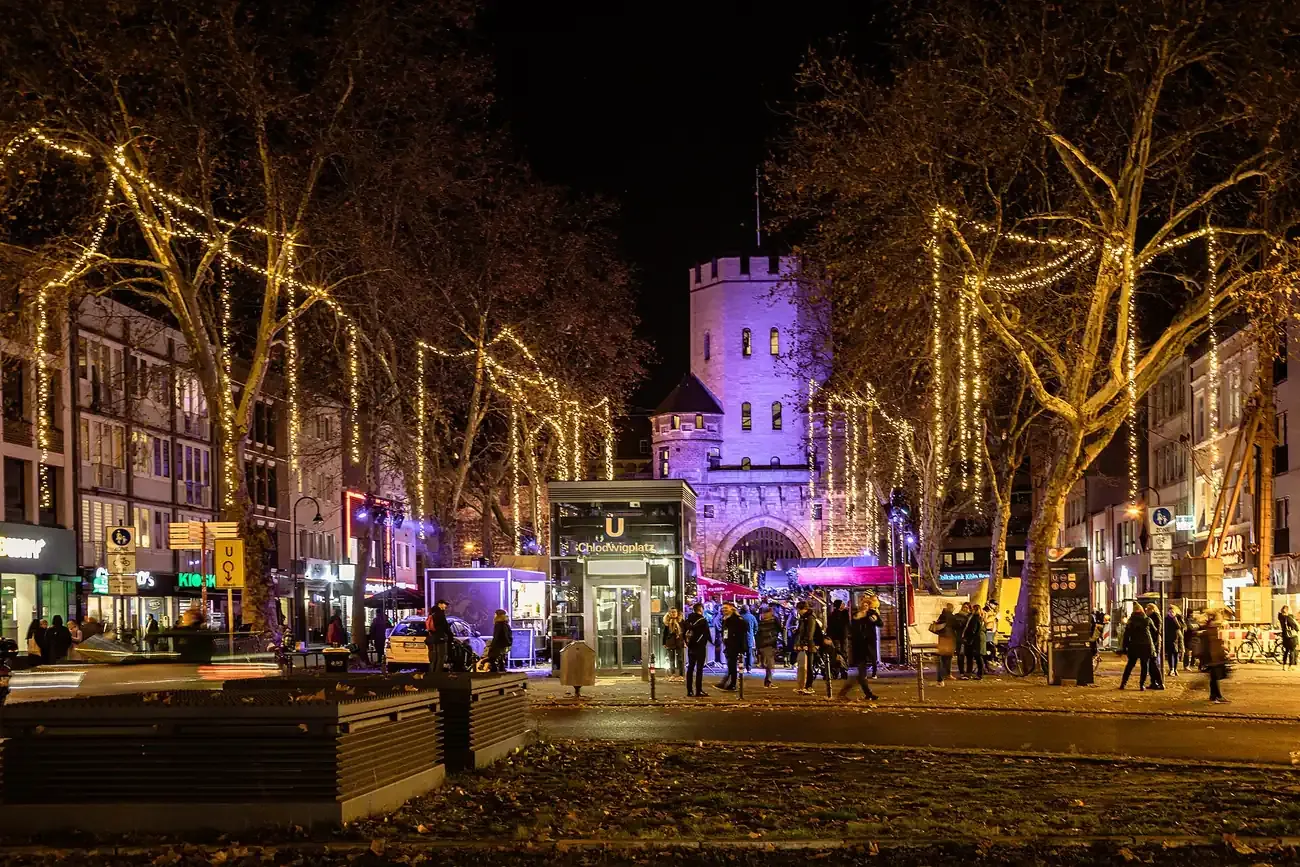 Christmas market on Chlodwigplatz with the lit Severinstorburg gate, Cologne