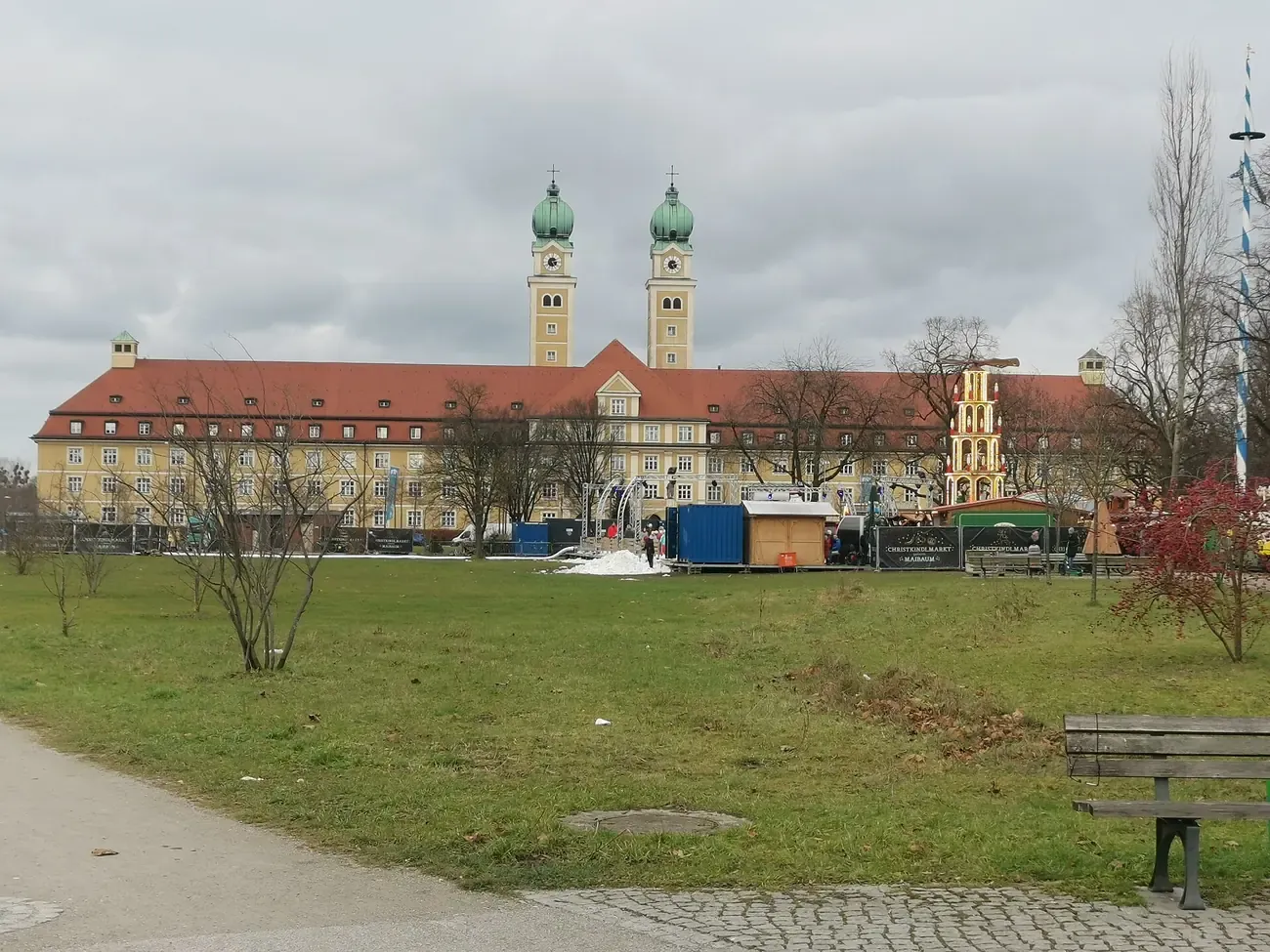 Huts and the mulled-wine pyramid of the Christmas market on Luise-Kiesselbach-Platz seen across the park, Munich