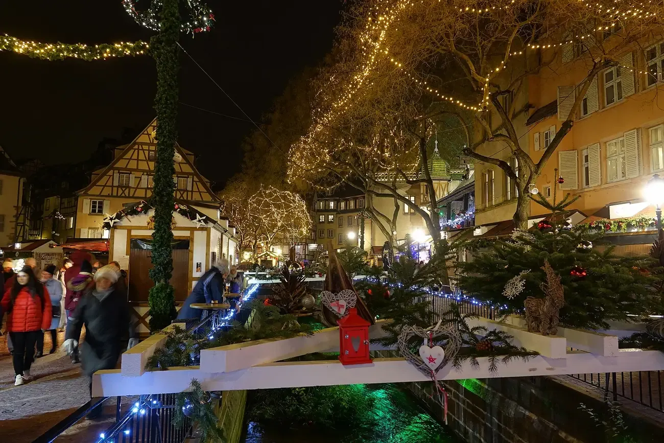 Chalets and lit trees of the Christmas market on place de l'Ancienne Douane in Colmar, by the Lauch, at night