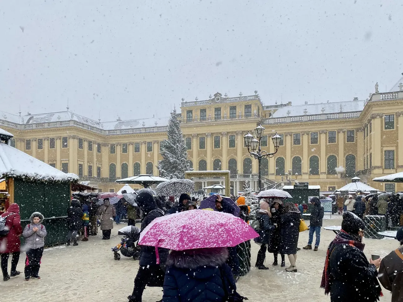 Christmas market stalls in the courtyard of Schönbrunn Palace in falling snow, Vienna