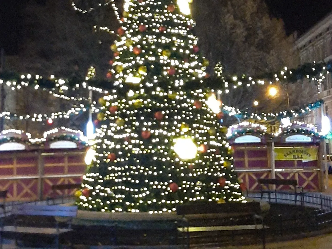 Lit Christmas tree and market huts on Tylovo náměstí at night, Prague