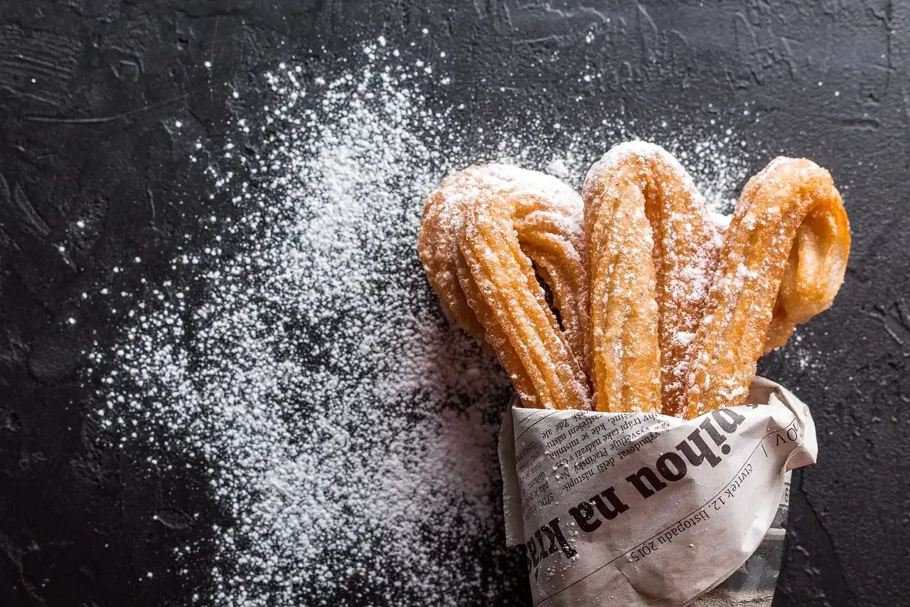 Freshly fried churros dusted with sugar in a paper wrap
