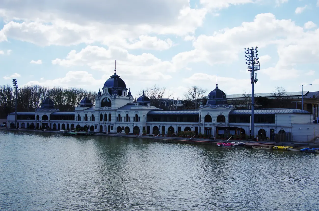 The lake in Budapest's City Park (Városliget) with the ice rink pavilion on the far shore under a cloudy sky