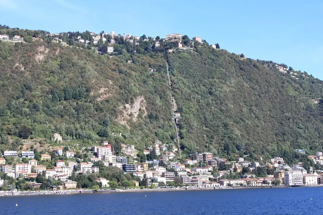 The straight line of the Como-Brunate funicular track cutting up the wooded hillside above the lake