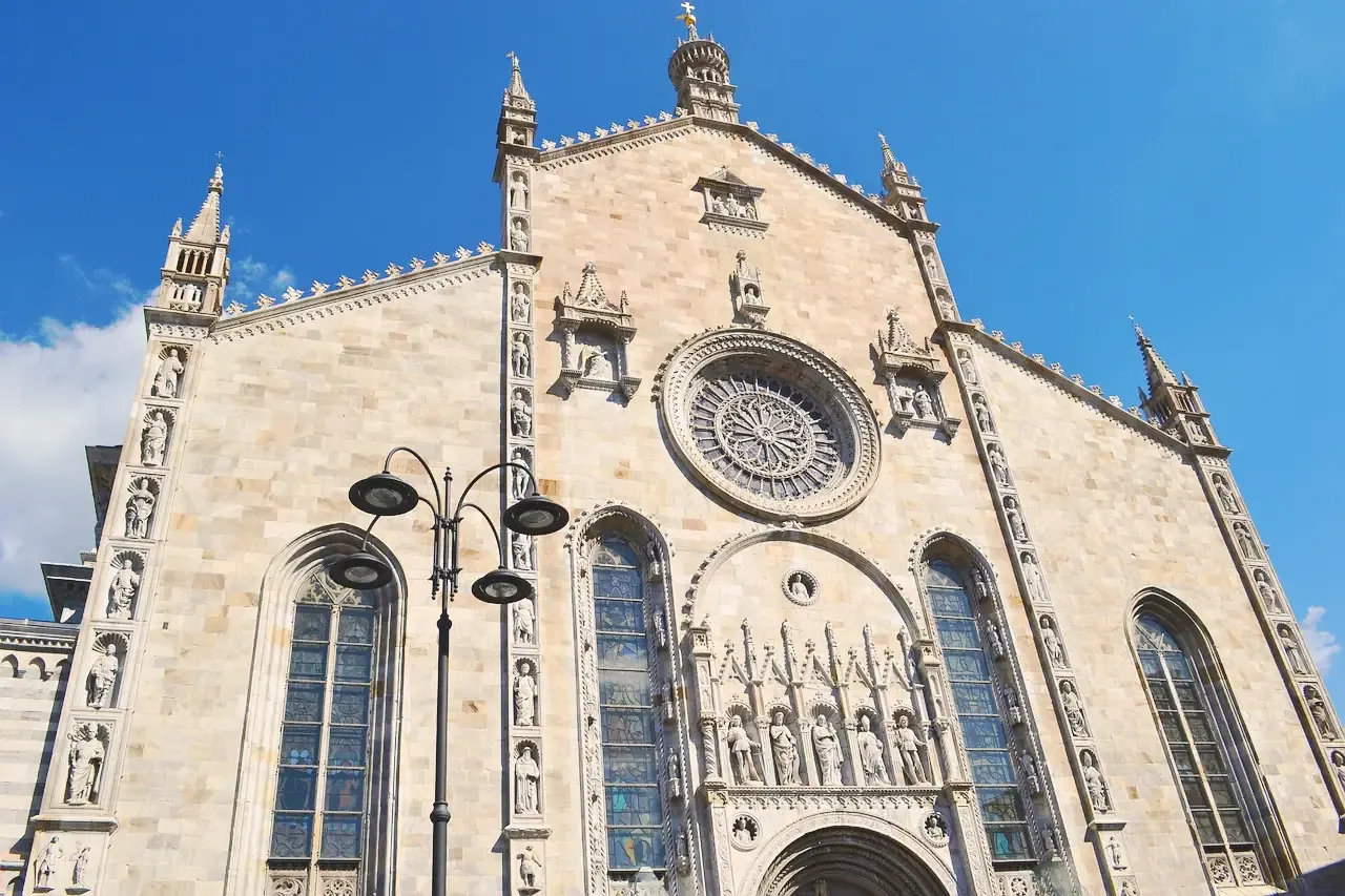 The Gothic marble facade of Como Cathedral with its rose window and statues
