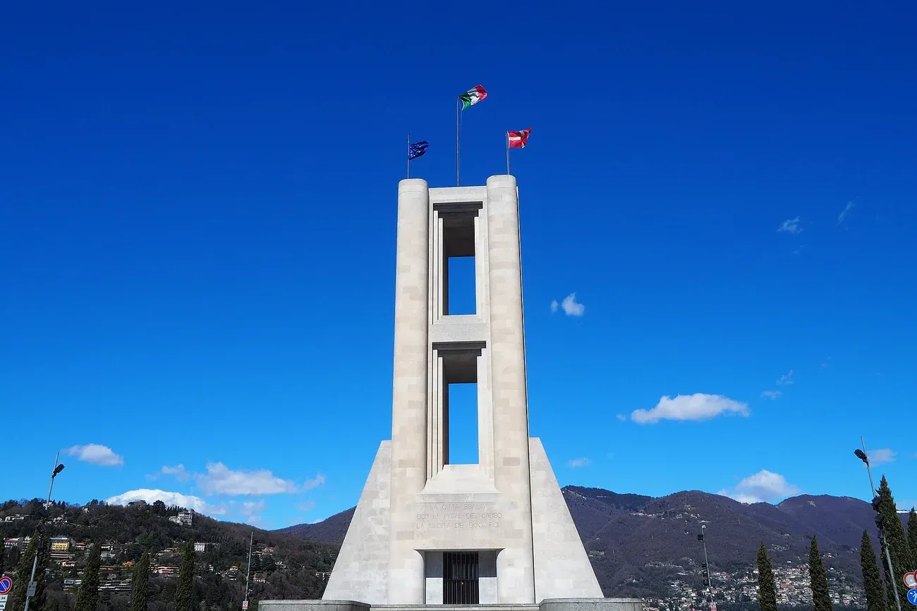 The tall stone war memorial Monumento ai Caduti on the Como lakefront against a blue sky