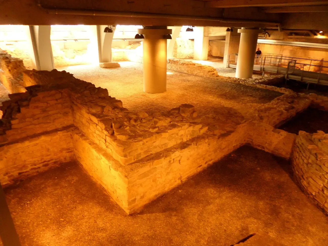 Lit stone foundations of the Roman baths of Como under the modern building in Viale Lecco